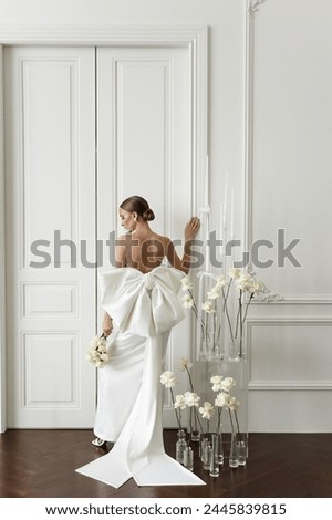 Elegant girl in white evening dress posing for fashion magazine. View from the back. Wedding photo of the bride.