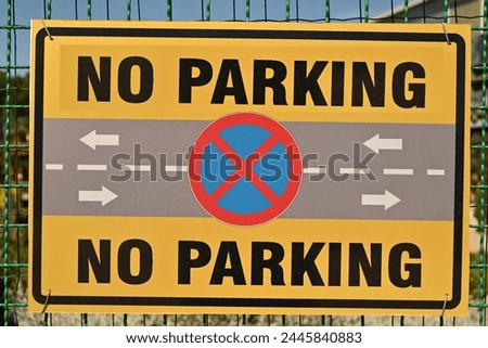 No Parking sign on fence in street