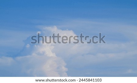 Clouds form an abstract image in the blue sky. The sky is bright during the day with blue and white clouds