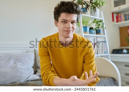 Portrait of handsome guy looking at camera, sitting on couch at home