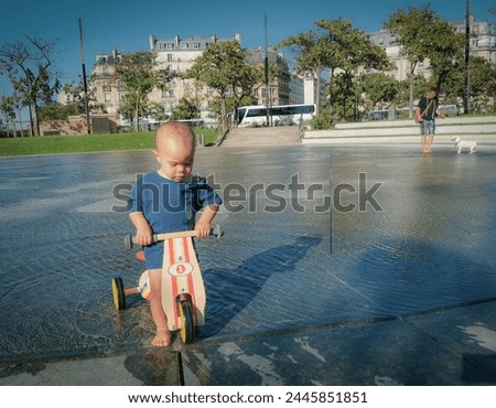 A boy is playing with the water fountains.He is so amused and enjoys it in the summer when the weather is too hot. Royalty-Free Stock Photo #2445851851