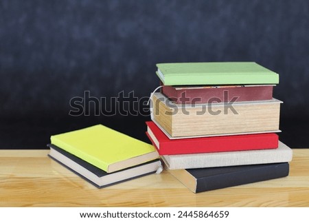 stack of books on wooden table against wooden wall. space for text, back to school concept
