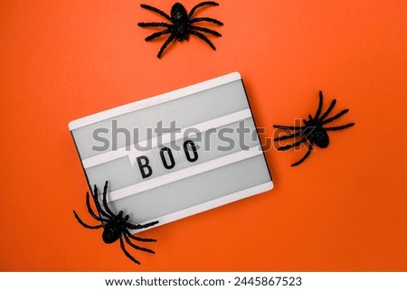 Minimal Halloween decor, lightbox with word Boo and spiders