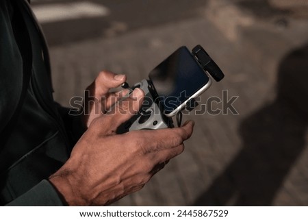 man's hands with radio remote control operating drone in mid-fli