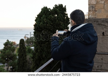 Man taking pictures of the seascape with his phone