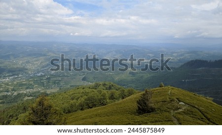 Serene View from the mountain peak of the green mountain landscape and small houses of the village conveys the calm beauty of nature. Photo.