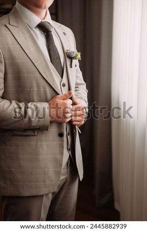 He is holding a grey curtain, dressed in formal attire.