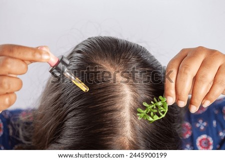 indian women using rosemary essential hair oil to prevent hair fall, closeup view