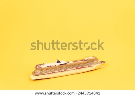 Miniature cruise ship isolated on yellow background in vertical format with copy space. Summer vacation concept