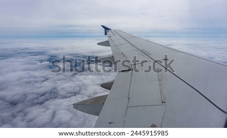 View of a air plane wing in the air during flight with atmosphere clouds in the background on the high altitude. 
