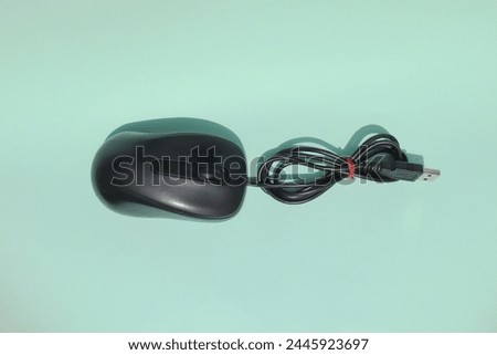 Top view of black computer mouse isolated on green paper. Mouse with wire