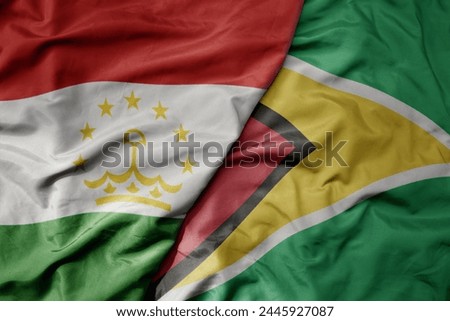 big waving national colorful flag of guyana and national flag of tajikistan. macro