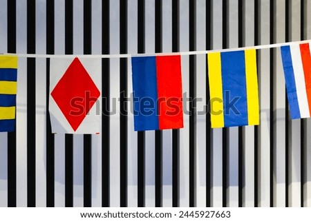 International maritime signal flags hang on the wall Royalty-Free Stock Photo #2445927663
