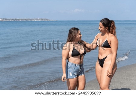 Two friends engage in a lively chat with the city skyline behind them on the beach.