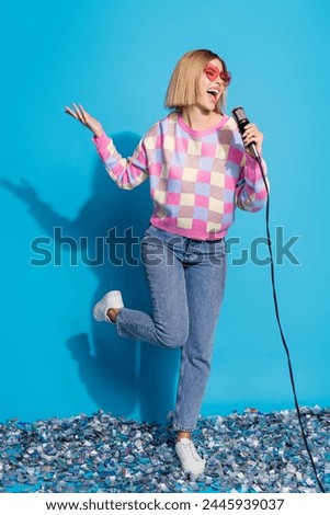 Vertical photo of pretty young girl sunglass celebrate party sing mic confetti wear trendy pink outfit isolated on blue color background