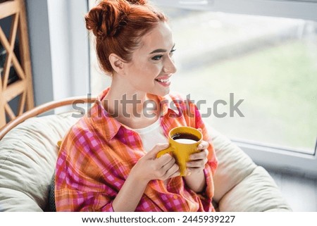 Photo of peaceful cute girl toothy smile hold fresh coffee mug look window imagine fantasize spend pastime house inside