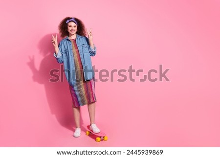 Full length photo of carefree friendly lady dressed jeans outfit showing two v-signs riding penny board empty space isolated pink color background