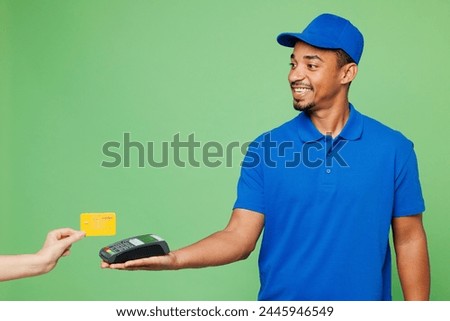 Delivery guy employee man he wear blue cap t-shirt uniform workwear work as dealer courier hold bank payment terminal to process acquire credit card isolated on plain green background. Service concept
