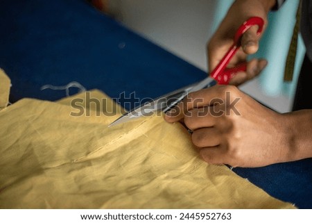 Close up photo of unrecognisable African American tailor using tailoring scissors to cut material for sewing