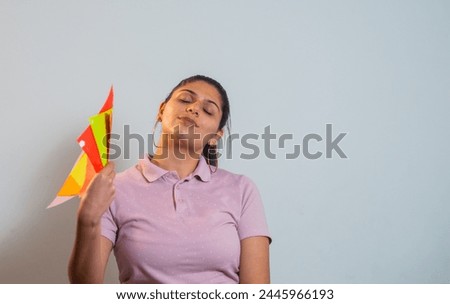 very calm young woman in a studio photo with a hand holding her colored papers and a hand venting. 