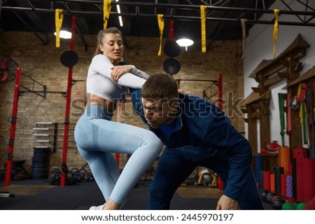 Young sports woman practicing self-defense technique with personal trainer