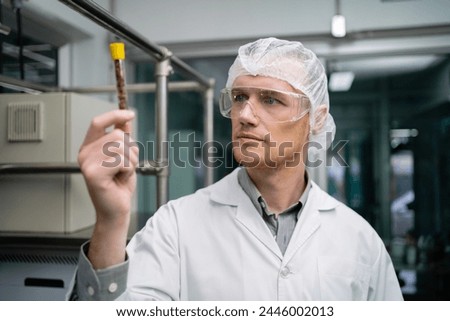A scientist wearing a lab coat and goggles is writing on a clipboard