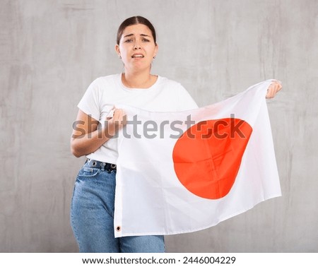 Frustrated girl with flag of Japan flag in her hands. Isolated on gray background