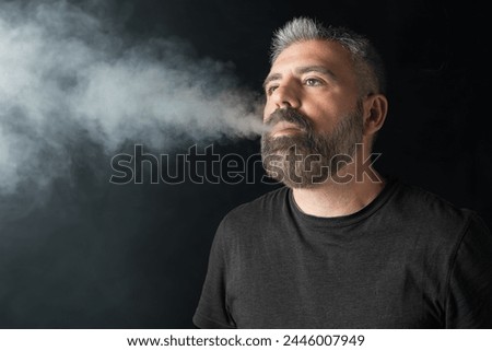Bearded Man Engrossed in Vaping: Middle-aged Serenity