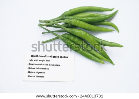 Green chillies with tag of text Health benefits of green chillies. White background. Concept, Chillies with good qualification for health. Photo for education. Teaching aid. Healthy food lesson.