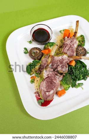 A delicious and healthy rib dish with mushrooms, broccoli, carrots and spinach on a white plate on a green background. Royalty-Free Stock Photo #2446038807