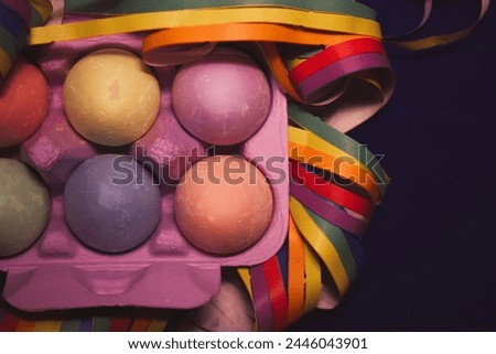 Painted colorful Easter eggs nestled in a violet box flatly. LGBT gay vibrant colors garland. Festive wallpaper, greeting card Festive springtime pic.