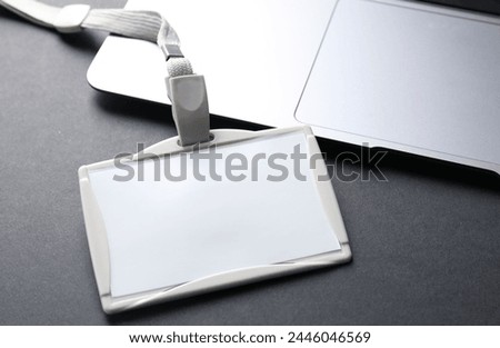 Blank badge and laptop on grey background, closeup