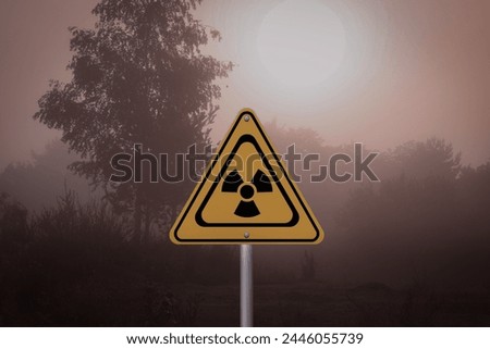 Radioactive pollution. Yellow warning sign with hazard symbol in rural area