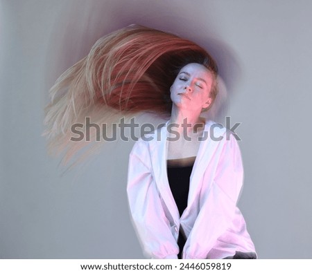 Fashionable portrait of beautiful young woman on grey background, long-exposure photography