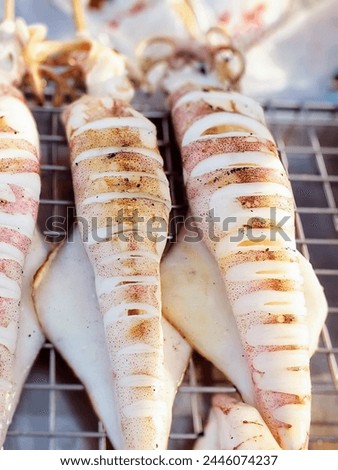a photography of squids are cooked on a grill with a lot of sauce.