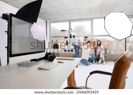 Male photographer showing photos to big family in studio