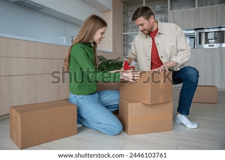 Happy couple packing cardboard box using sticky tape to move in new apartment together. Family wife husband prepare to relocate in flat house. Relocation mortgage, life changes, buying real estate. Royalty-Free Stock Photo #2446103761
