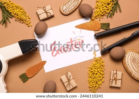 Composition with greeting card, hairdresser's tools and Easter decor on brown background