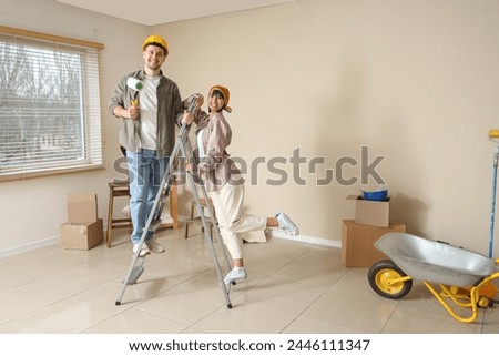 Young couple with paint roller and stepladder during repair in their new house
