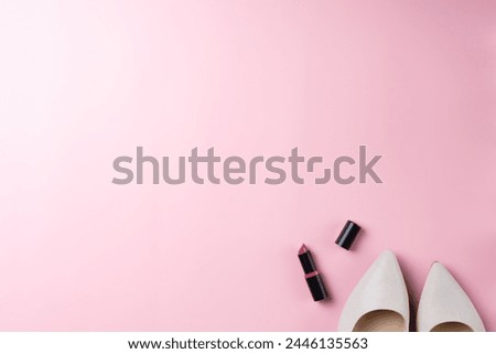 Pink background with women's shoes and lipstick. Top view point, flat lay. Space for text