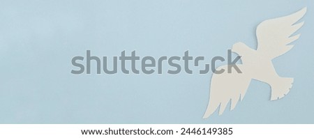 White paper origami bird on blue background. World Day of Peace. Day Against Humiliation. International Day Of Human Fraternity. International Day of Living Together in Peace. Banner