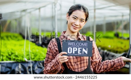 Portrait of young asian woman farmer holding open sign on hydroponics organic vegetable farm, Owner female of the hydroponics salad garden takes customer orders to pack fresh vegetables.
