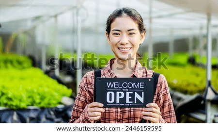Portrait of young asian woman farmer holding open sign on hydroponics organic vegetable farm, Owner female of the hydroponics salad garden takes customer orders to pack fresh vegetables.