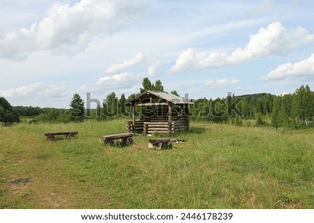 Photo, gazebo with benches on a green meadow, blue sky, summer, sun, warmth, heat, picnic spot, outdoor dining, nature, countryside, shelter from rain in the forest