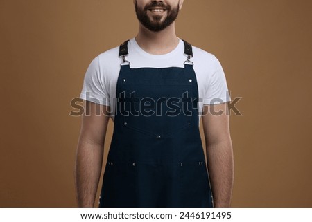 Smiling man in kitchen apron on brown background, closeup. Mockup for design