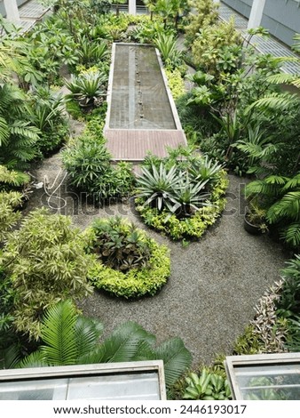 A picture of the garden inside the building is full of beautiful flowers and there is a pond