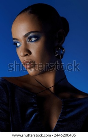 Young African American woman in a black dress with bag, captivating blue eyes. Royalty-Free Stock Photo #2446200405