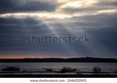 The sun's rays break through the clouds and illuminate the lake.
The picture was taken at Lake Burtnieks in Latvia.