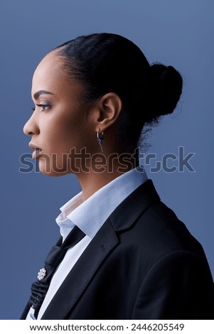 Young African American woman in a suit and tie gazes thoughtfully to the side. Royalty-Free Stock Photo #2446205549
