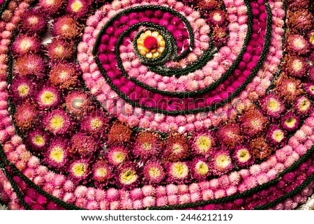 A flower arrangement with a spiral design. The flowers are pink and yellow. The arrangement is very colorful and eye-catching